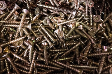 Pile of pozidriv head type screws, with a blurred background.