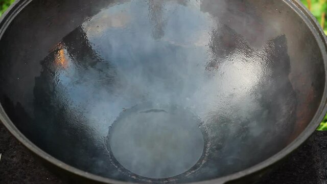 oil and fat are heated in an open pot. large cast iron cauldron on an open fire. empty pan