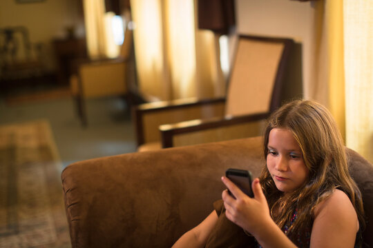 Girl sitting on sofa texting on smartphone - Powered by Adobe