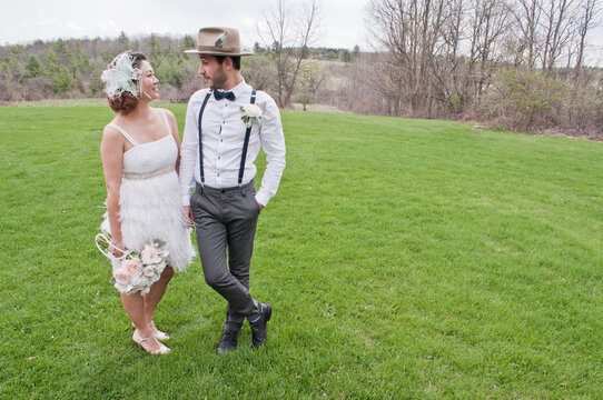 Portrait of bride and groom standing in field, face to face, smiling