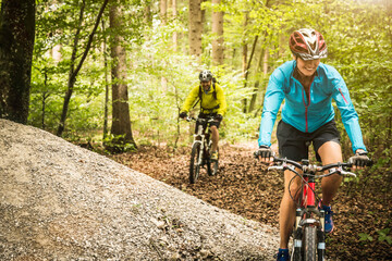 Mature mountain biking couple cycling through forest