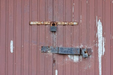 
two rusty padlocks hanging on a old metal gate