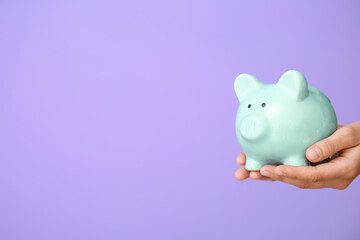 Female hands with piggy bank on color background
