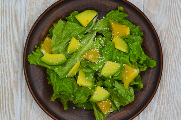 fresh summer homemade salad of vegetables and fruits, orange, lettuce, avocado and sesame seeds, healthy food, organic, vegetarian eco health and immunity products