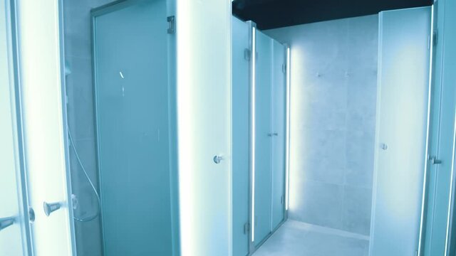 Indoor view of modern stylish commercial shower cubicles and changing rooms inside professional gym. Sports club interior.