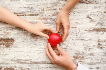Hands of family with heart on wooden background