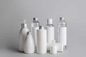 Different bottles of cosmetic products on gray background