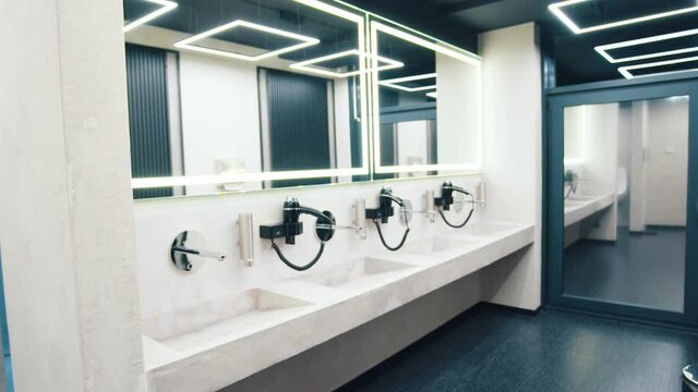 Inside view of stylish white clean toilet room and shower cabins in modern gym sports club. Modern interiors concept.