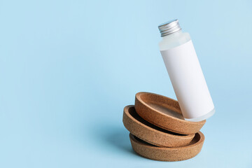 Bottle of cosmetic product and plates on color background