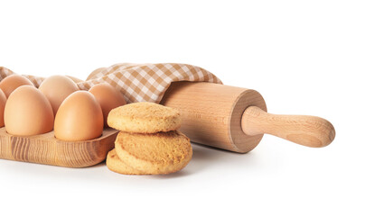 Cookies, eggs and rolling pin on white background