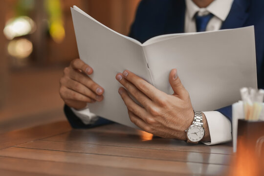 Young Businessman Reading Magazine In Cafe, Closeup