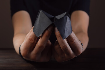 Hands of male fortune teller with paper cootie catcher on dark background