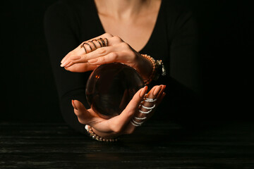 Fortune teller with crystal ball on dark background