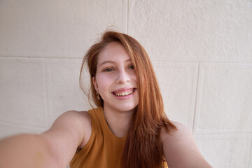 A beautiful red-haired white Latina woman smiles towards the camera as she takes a selfie