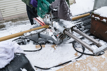 雪降りの中での手摺取り付け工事アルミ樹脂巻手すり棒のカット