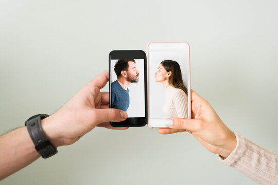 Hands holding two smartphones with photos of a couple kissing