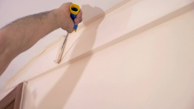worker passing the roller brush along ceiling frame to finishing work