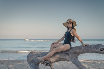 mujer posando sobre un árbol en bikini y sombrero