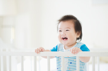 ベビーベッドで笑う赤ちゃん  