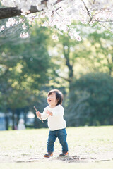 桜の樹の下で枝を持つ男の子