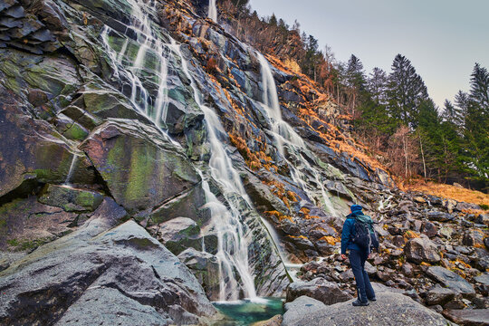 Young man admiring Nardis waterfalls in Val di Genova, Adamello-Brenta Natural Park  in the northern Italy