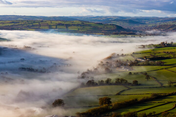 Green fields and rural farmland covered in low hanging mist and fog