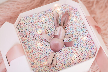 Gift box with pink rabbit. Greeting card Festive holiday pastel backdrop. Birthday congratulations....