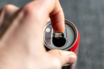 Pulling the tab of a beverage can with a left male hand. Opening a refreshment drink like cola or...