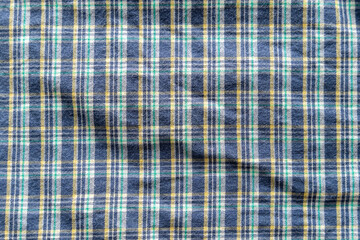 Plaid textile pattern of a blue green yellow garment. Fabric structure closeup of a vintage fashion...