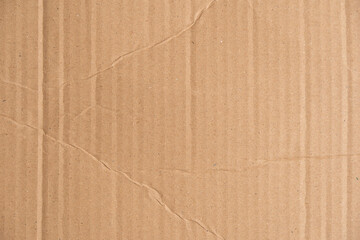 Brown corrugated cardboard texture with wrinkles and creases. Carton structure of a packaging box used for shipping and delivery. Damaged parcel material.
