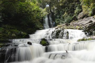 Fototapeta na wymiar A man is looking at the water flowing through McLean falls. New Zealand