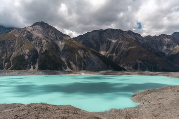 Fototapeta na wymiar Tasman Lake and mountain range on a cloudy sunny day. New Zealand travel destination