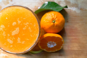 Fresh handmade healthy mandarin juice with two mandarins and a leaf in the background