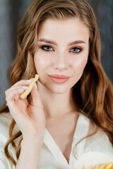 beautiful young woman with long hair and makeup eating French fries.