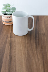 White mug on wooden background with a little houseplant