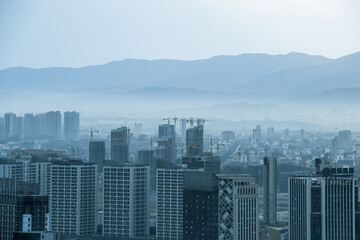 Gray industrial city, surrounded by mountains in the distance
