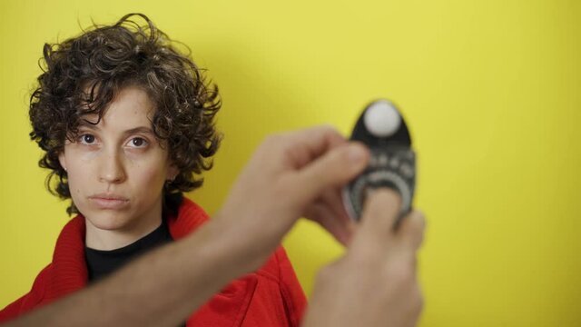 Photographer measures light blocks model face she moves to stay in the spotlight. Funny moment on set. Female model tries to stay on camera avoids light meter. Amusing gesture diva like attitude