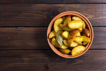 Slices of baked potatoes with herbs in a plate on a wooden table. Horiz. Horizontal orientation, no people, copy space, close-up