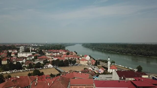 A drone view of a river surrounded by trees and buildings in Brcko, Bosnia and Herzegovina shot in HD