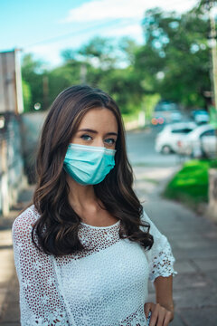 Shallow Focus Of An Adult Brunette Female Wearing A Lace Shirt With Facemask And Posing Outdoors