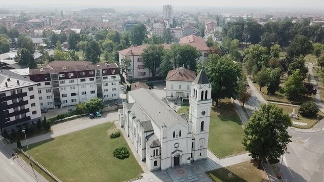 A drone view of the Sacred Heart Church surrounded by greenery in Bosnia and Herzegovina shot in HD