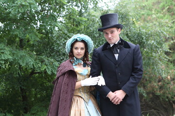 Man and woman in 19th century costumes walk in the park