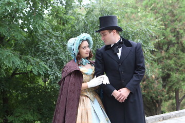 Man and woman in 19th century costumes walk in the park