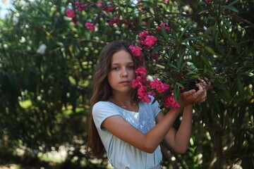 A girl walks in the park near a blooming oleander