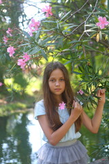 A girl walks in the park near a blooming oleander