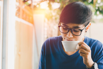 Asian woman hold white cup of black coffee on hand for a drink in the morning at home with sunlight. Coffee and healthy concept.