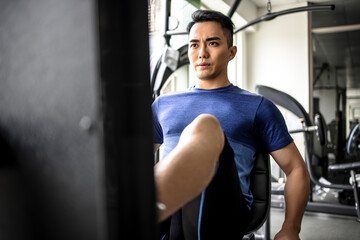 Fototapeta na wymiar Asian young man doing leg presses in gym