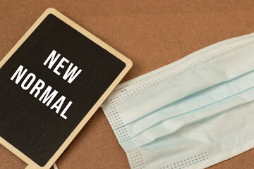 Fototapeta premium A chalk board with a face mask says the new normal separates the wood floors.