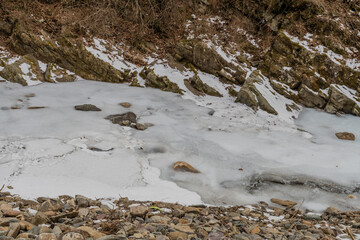 Water in river with rocky shoreline frozen.