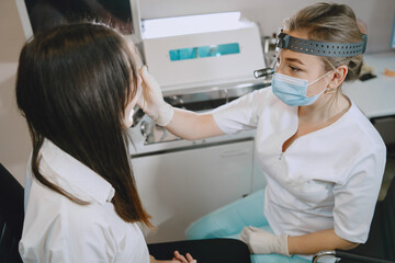 Woman patient in the medical office. Doctor in medical mask. Lor checks the woman' mouth.